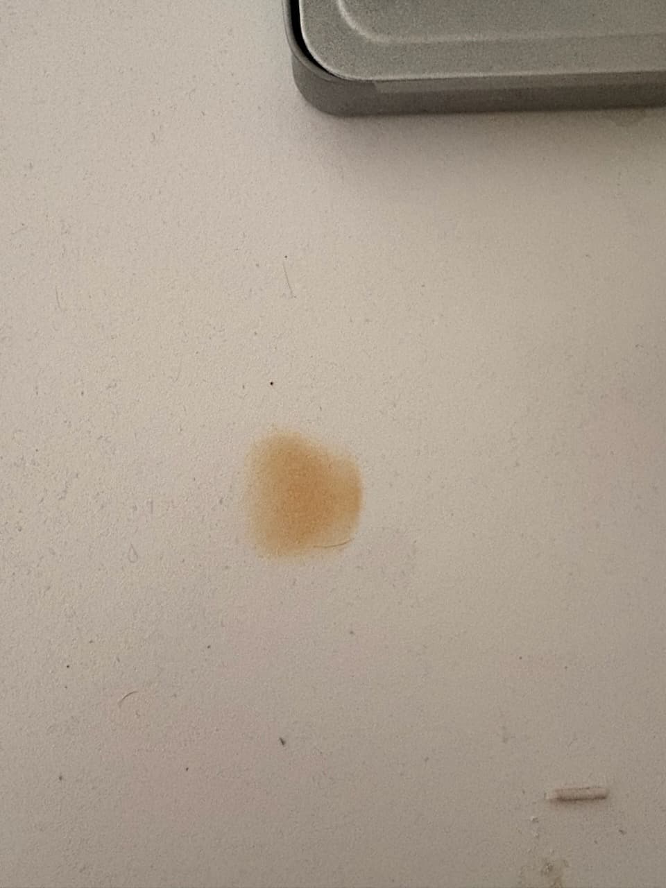 Before: a brown heat burn mark on a white engineered stone benchtop.