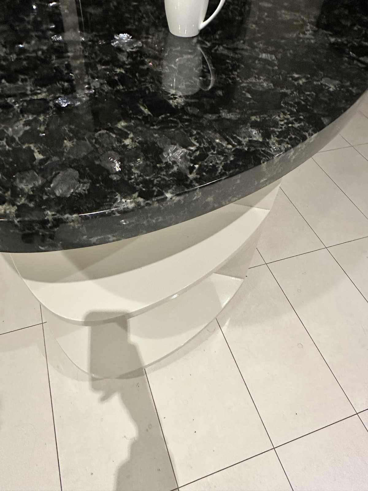 After: the same dark stone benchtop edge with the chip filled and polished flush.